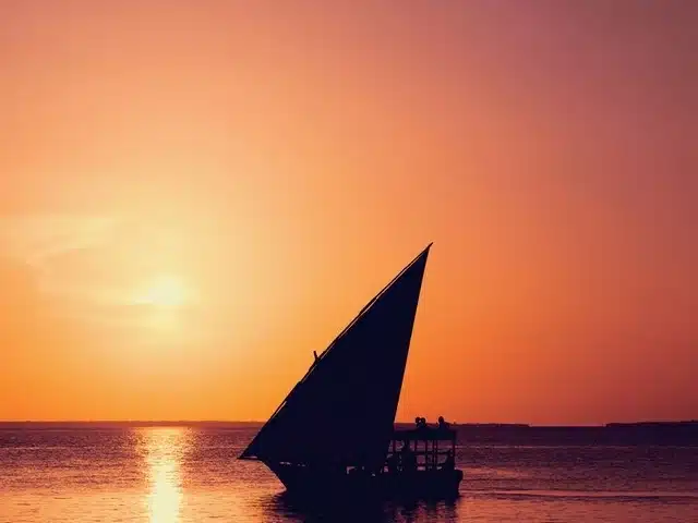 Coucher de soleil à Nungwi, Zanzibar : un dhow navigue sur le lagon au crépuscule