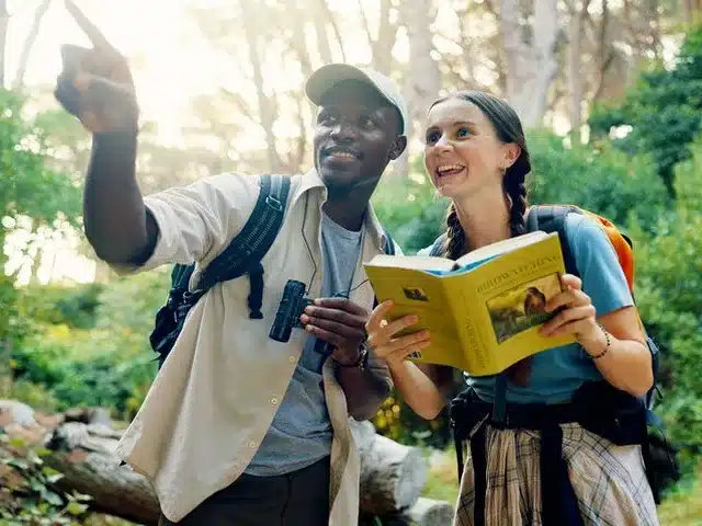 Guide local accompagnant une voyageuse lors d’une observation d’oiseaux en Tanzanie, pendant un safari nature